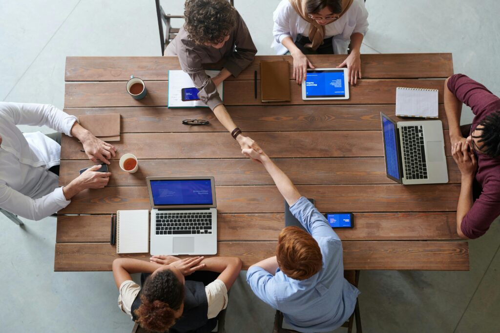 Overhead view of colleagues in a work meeting using laptops and tablets, emphasizing teamwork and technology.Shark Estimation